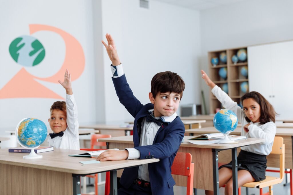 Students in a classroom eagerly raising their hands during a lesson.